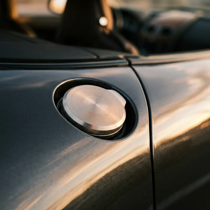 Close-up of a car's fuel cap at golden hour
